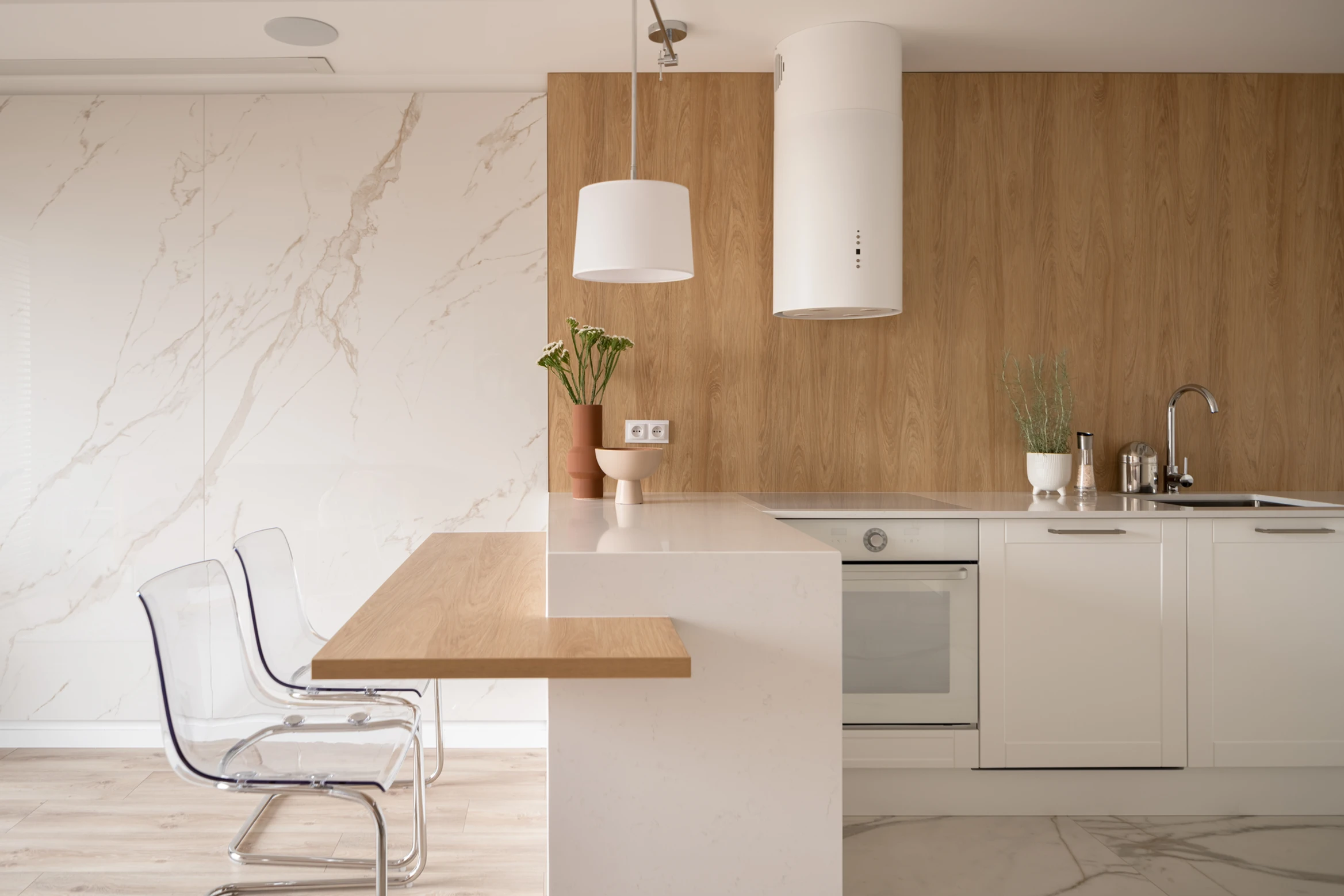 Modern kitchen trends with white cabinets, wood accents, marble backsplash, transparent chairs, and potted plants.