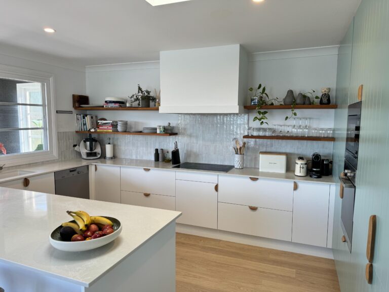 Modern kitchen with white cabinets and wood shelves, featuring Collaroy Plateau Door & Benchtop Reface.