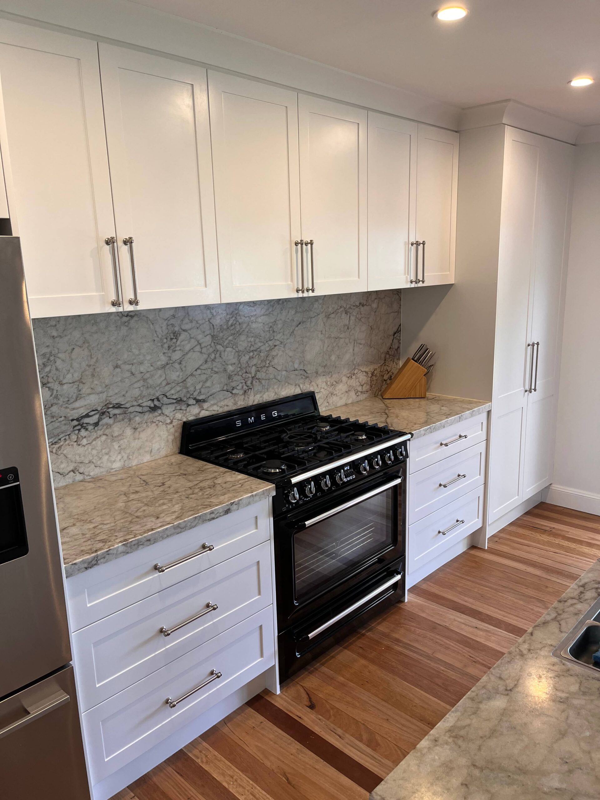 Modern kitchen with white cabinets, marble countertops and backsplash in Collaroy Plateau renovation.