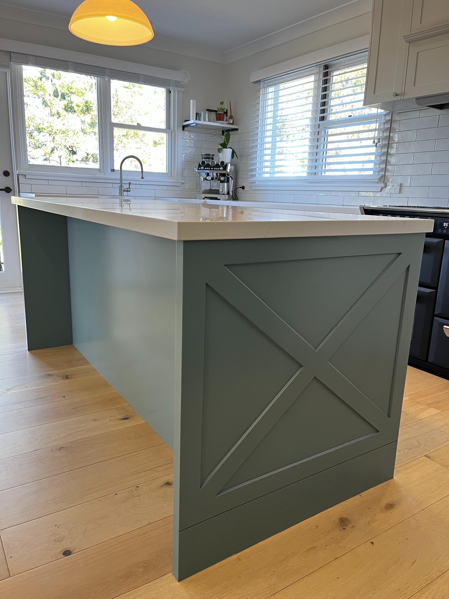 Modern kitchen island with pale green crisscross base and white countertop by Red Hot Kitchens in Curl Curl.