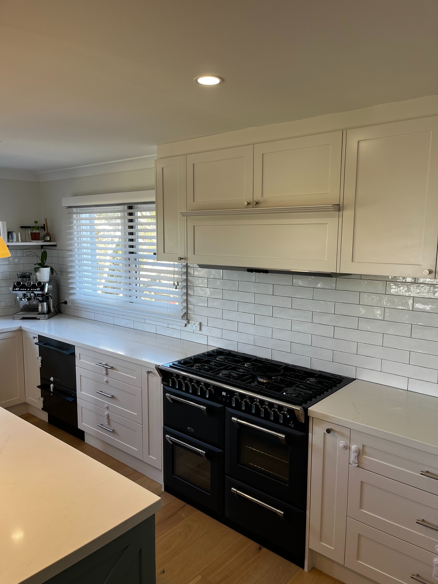 Modern kitchen in Curl Curl featuring custom cabinetry, subway tile, white cabinets, and natural light.