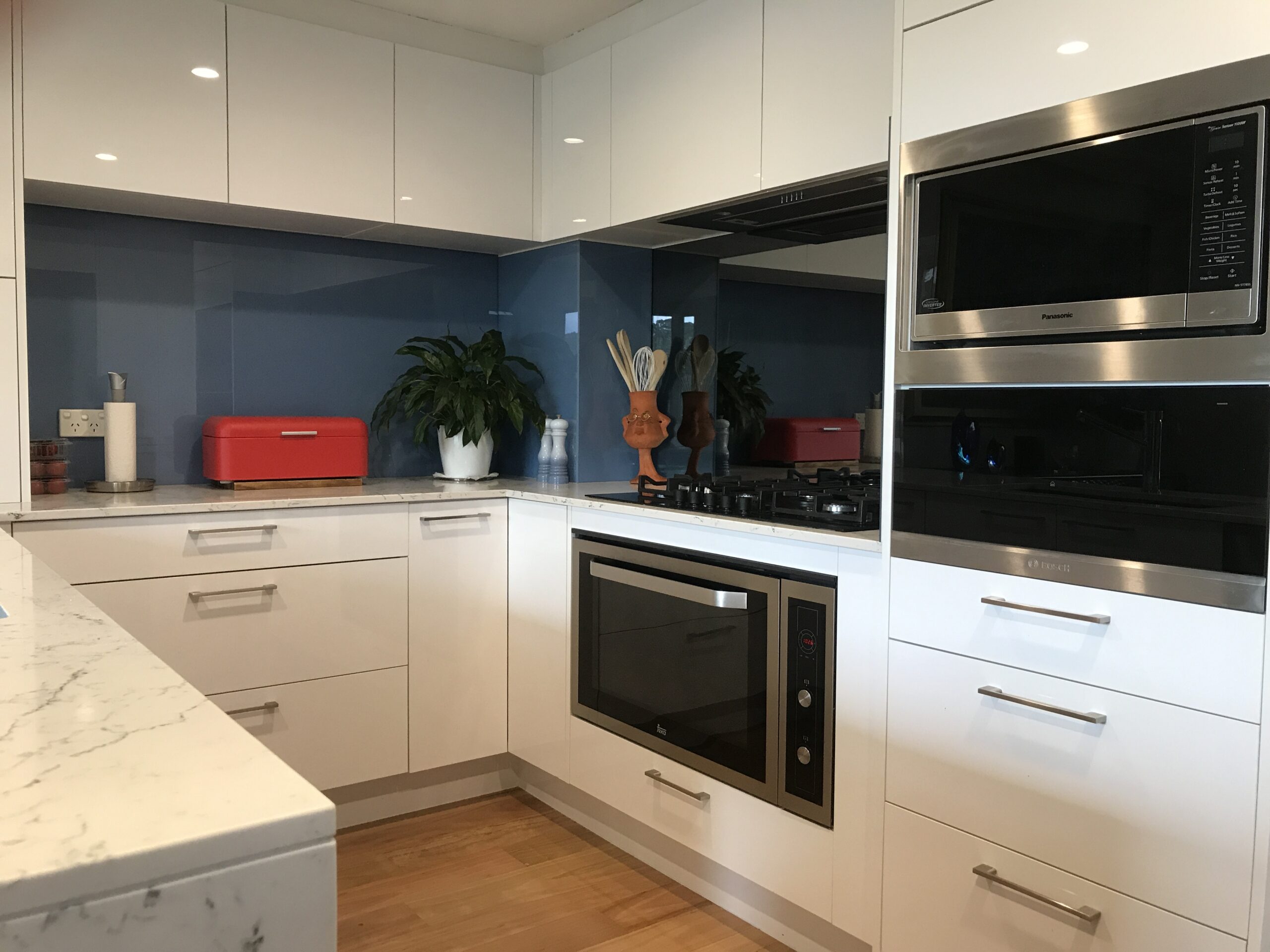 Custom kitchen fit-out in Brookvale with white cabinets, blue backsplash, red accents by Red Hot Kitchens.