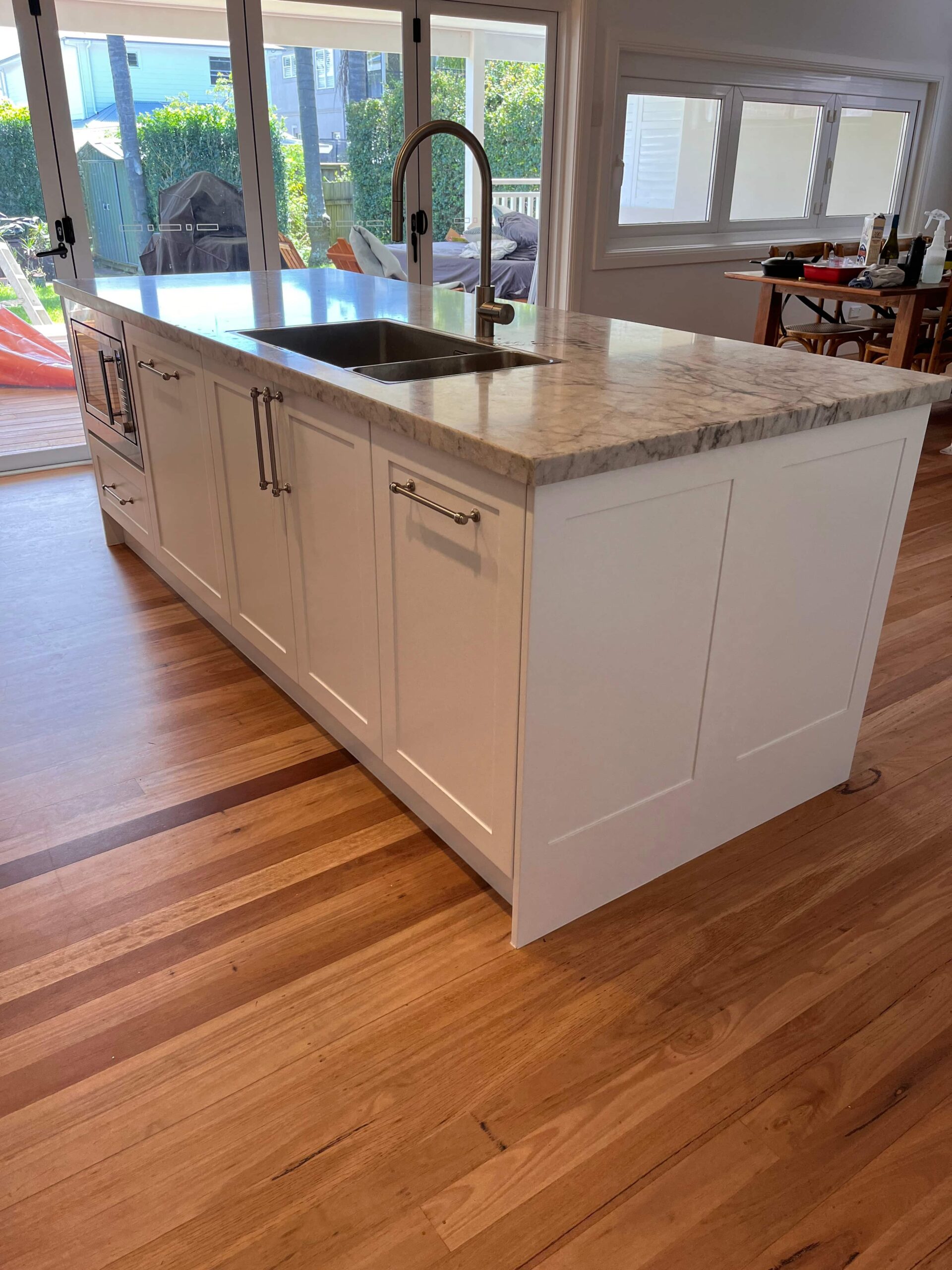 Kitchen renovation in Collaroy Plateau with a white island, marble countertop, and natural light by Red Hot Kitchens.