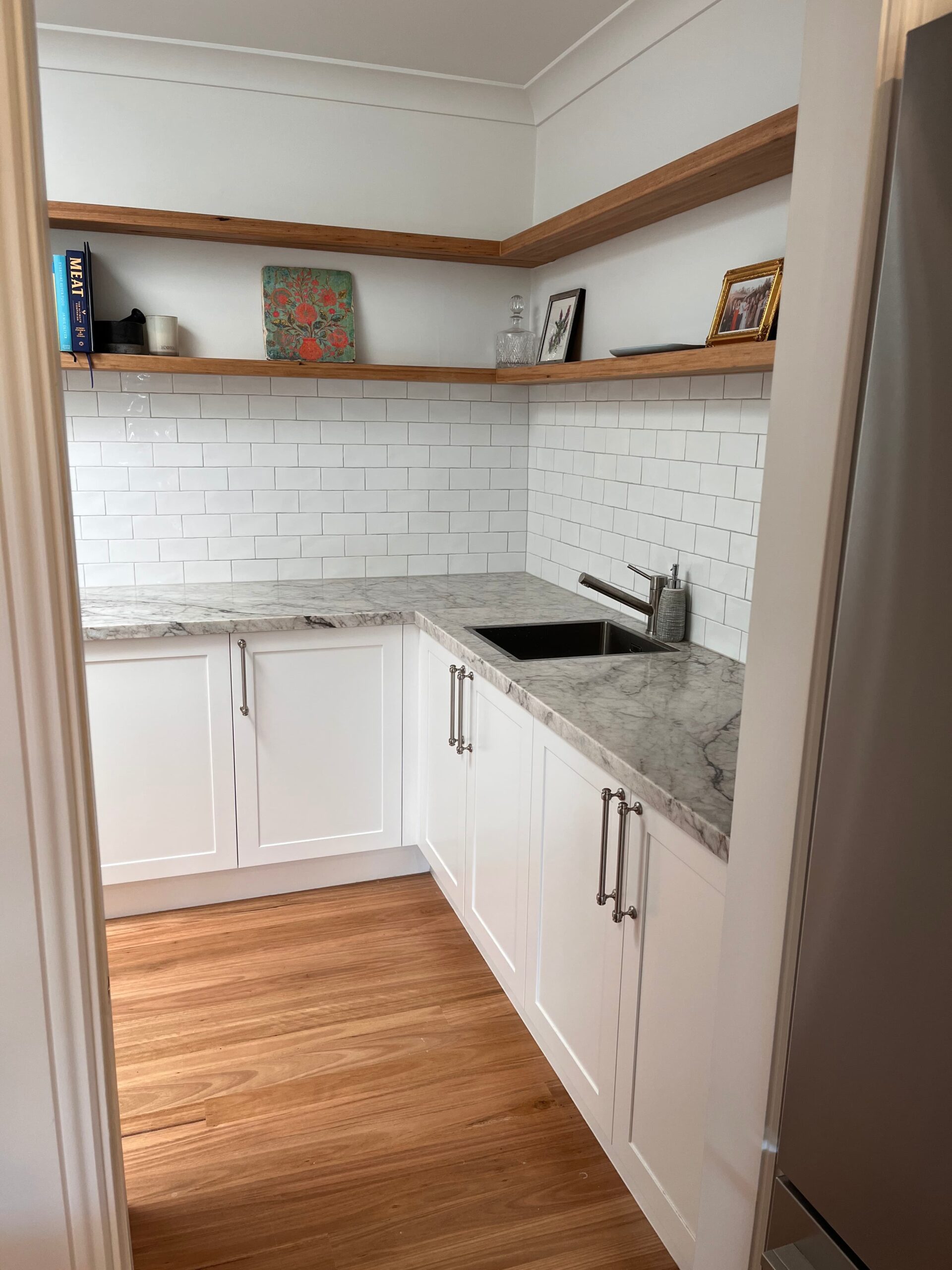 Stylish small kitchen in Collaroy Plateau with white cabinets, marble counter, and open shelves by Red Hot Kitchens.