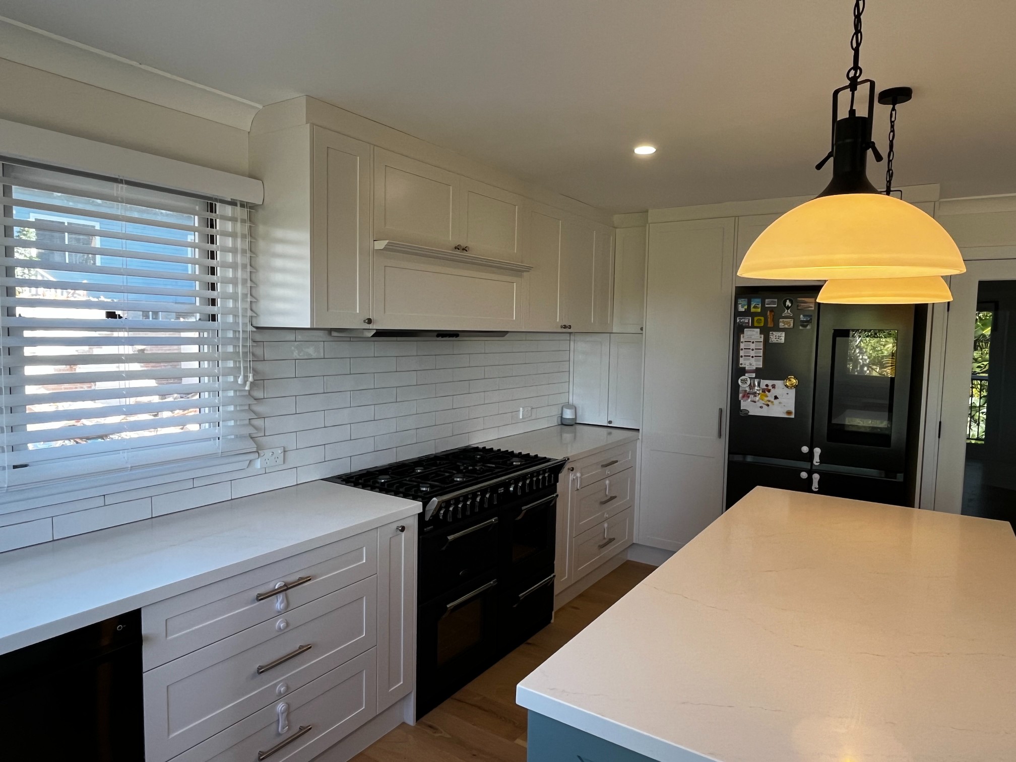 Modern kitchen with white cabinets, subway tile backsplash, black stove, refrigerator, and island countertop.