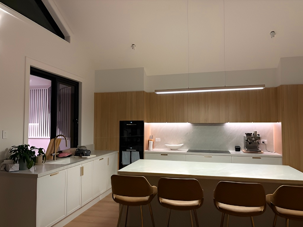 Modern kitchen North Curl Curl with marble island, brown bar stools, wood cabinets, built-ins, and lighting.