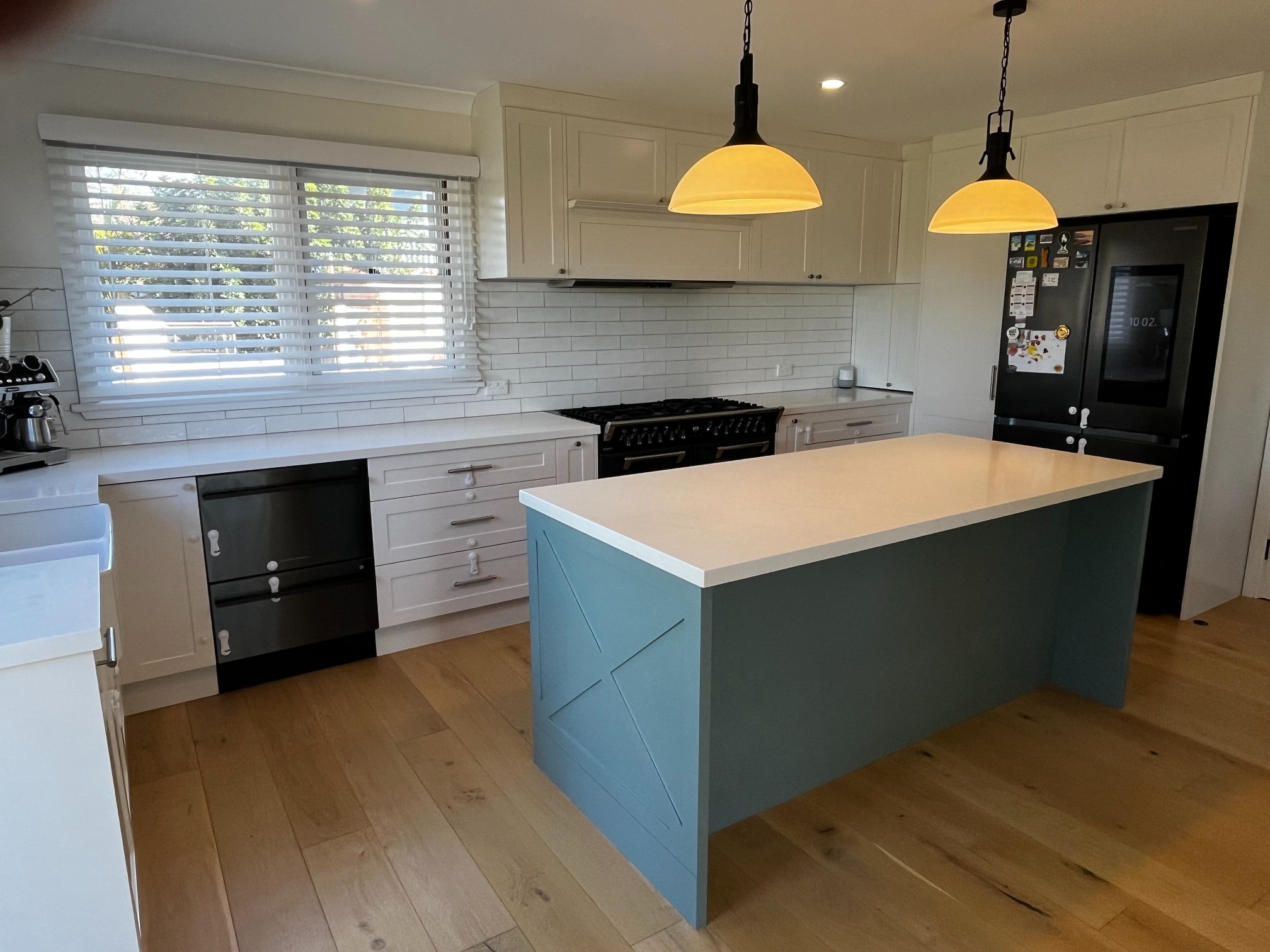 Modern kitchen by Red Hot Kitchens with white cabinets, blue island, and black appliances in Curl Curl.