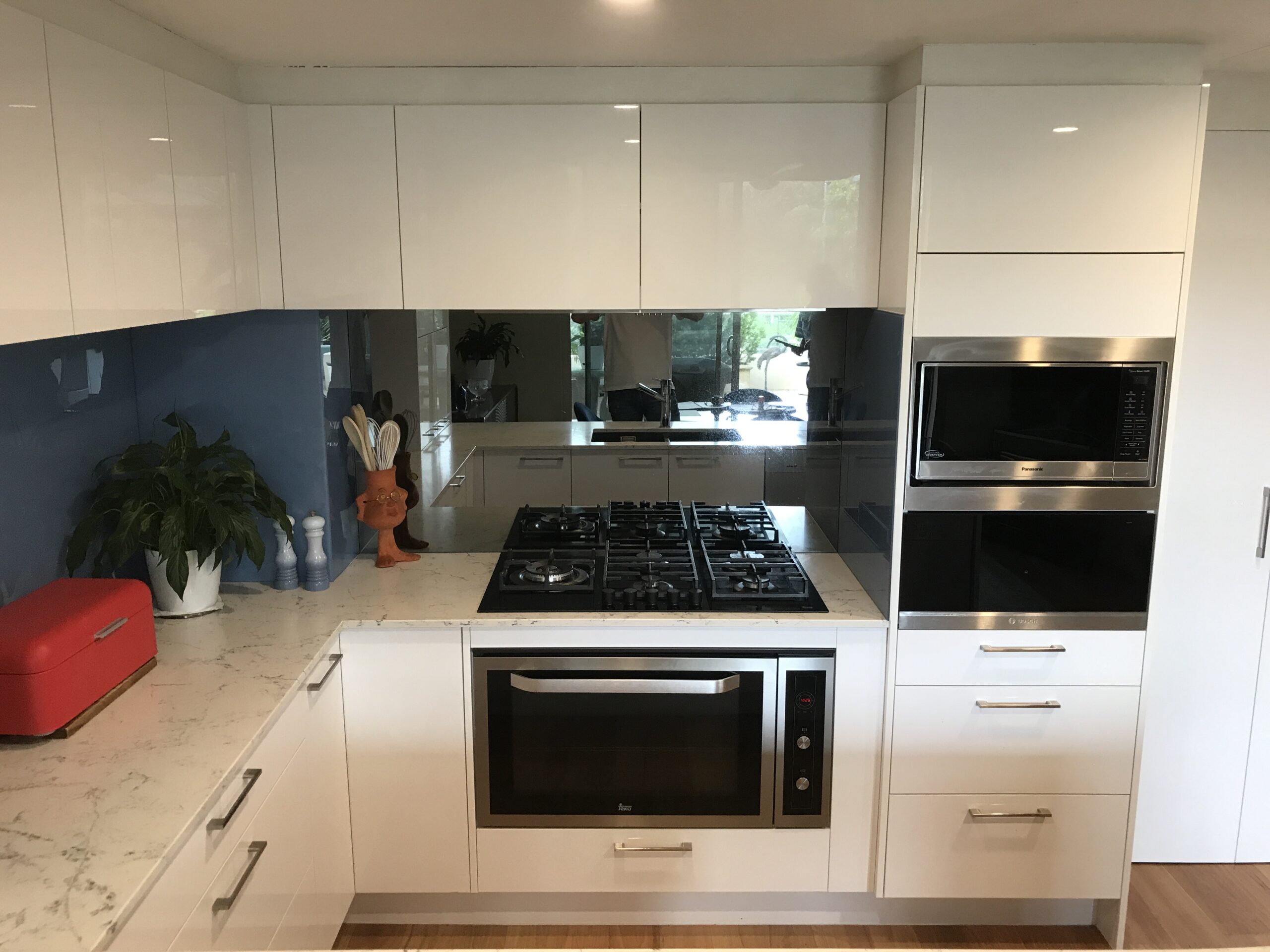 Modern kitchen with white cabinets, marble countertop, gas cooktop, wall oven—Red Hot Kitchens Brookvale.