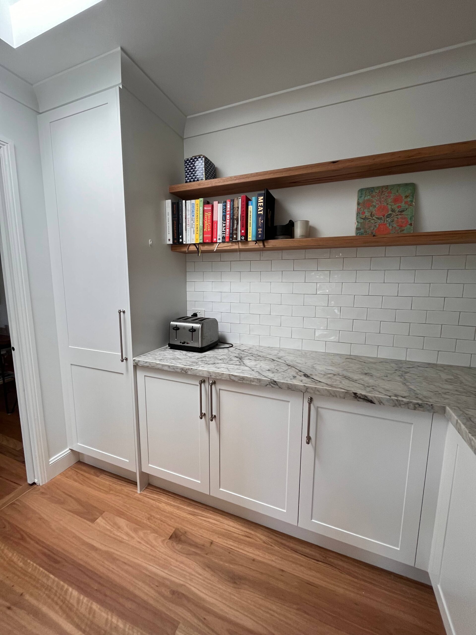 Modern kitchen with white cabinets, marble countertop, subway tile backsplash, and Red Hot Kitchens design.