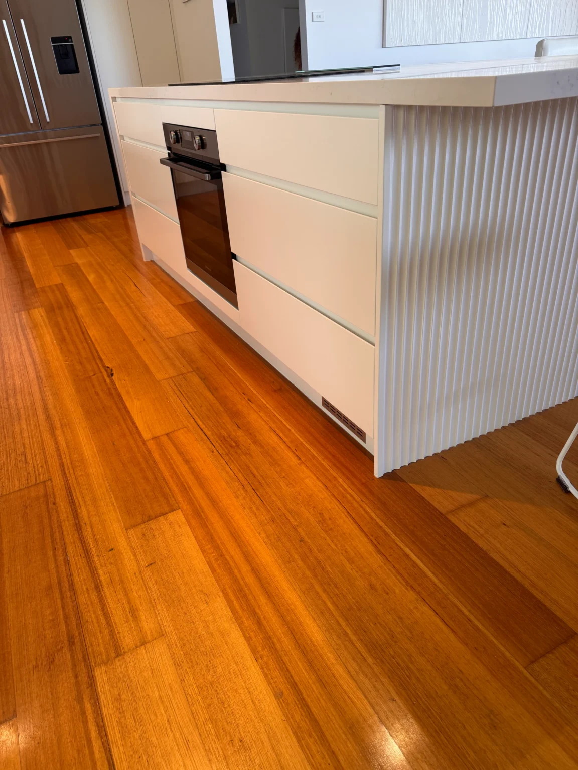 Allambie Heights kitchen island with wide white drawers, a built-in oven and fluted panels beneath the breakfast bar.