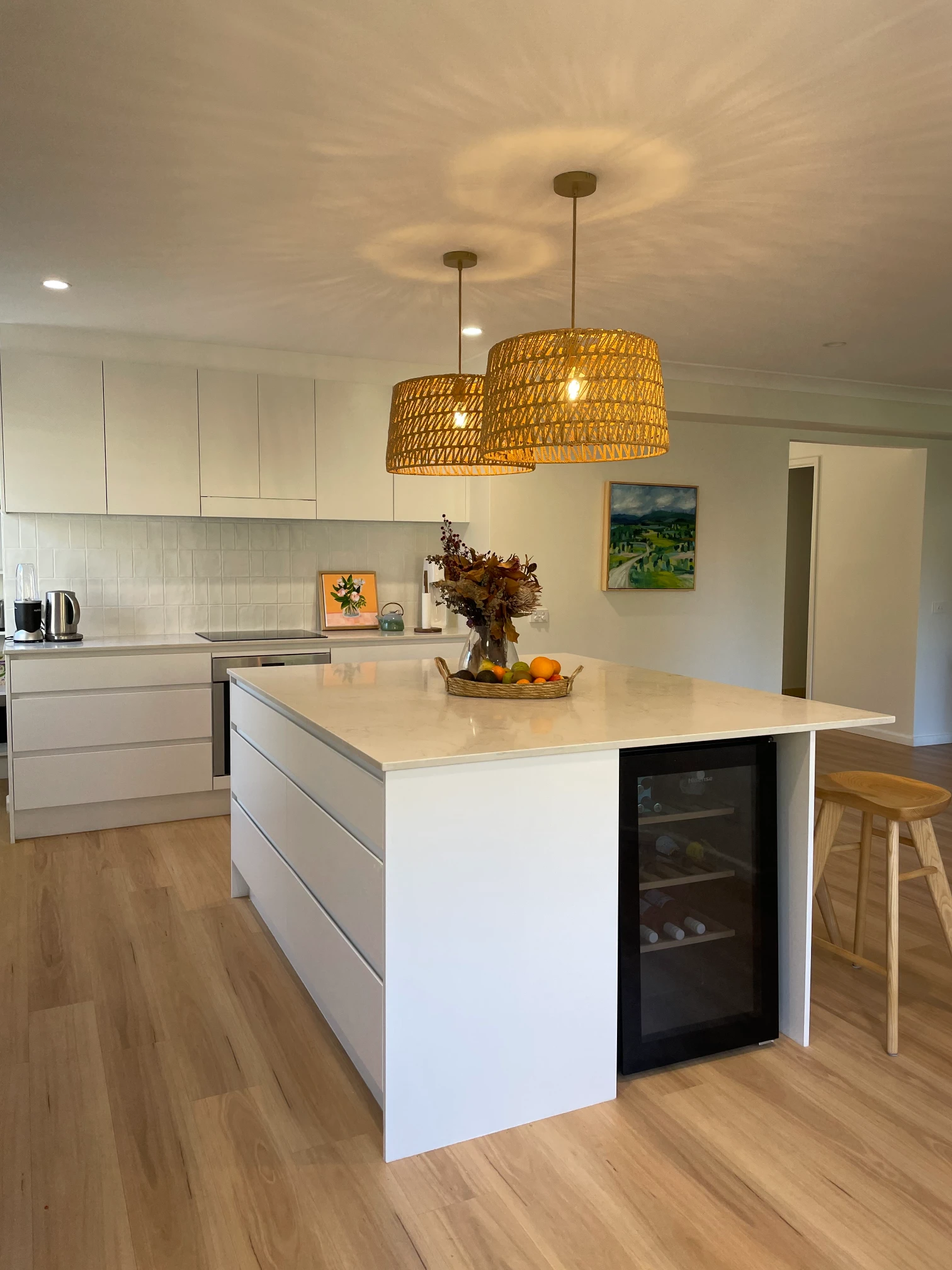Cromer kitchen island with a built-in wine fridge, white drawers, a pale veined benchtop and breakfast seating.