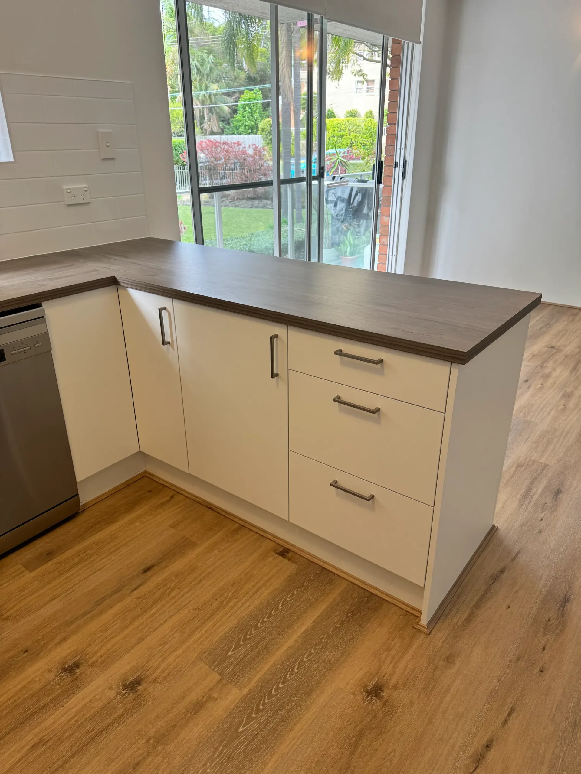 Refaced white peninsula with drawers in a Freshwater kitchen opening to the living area