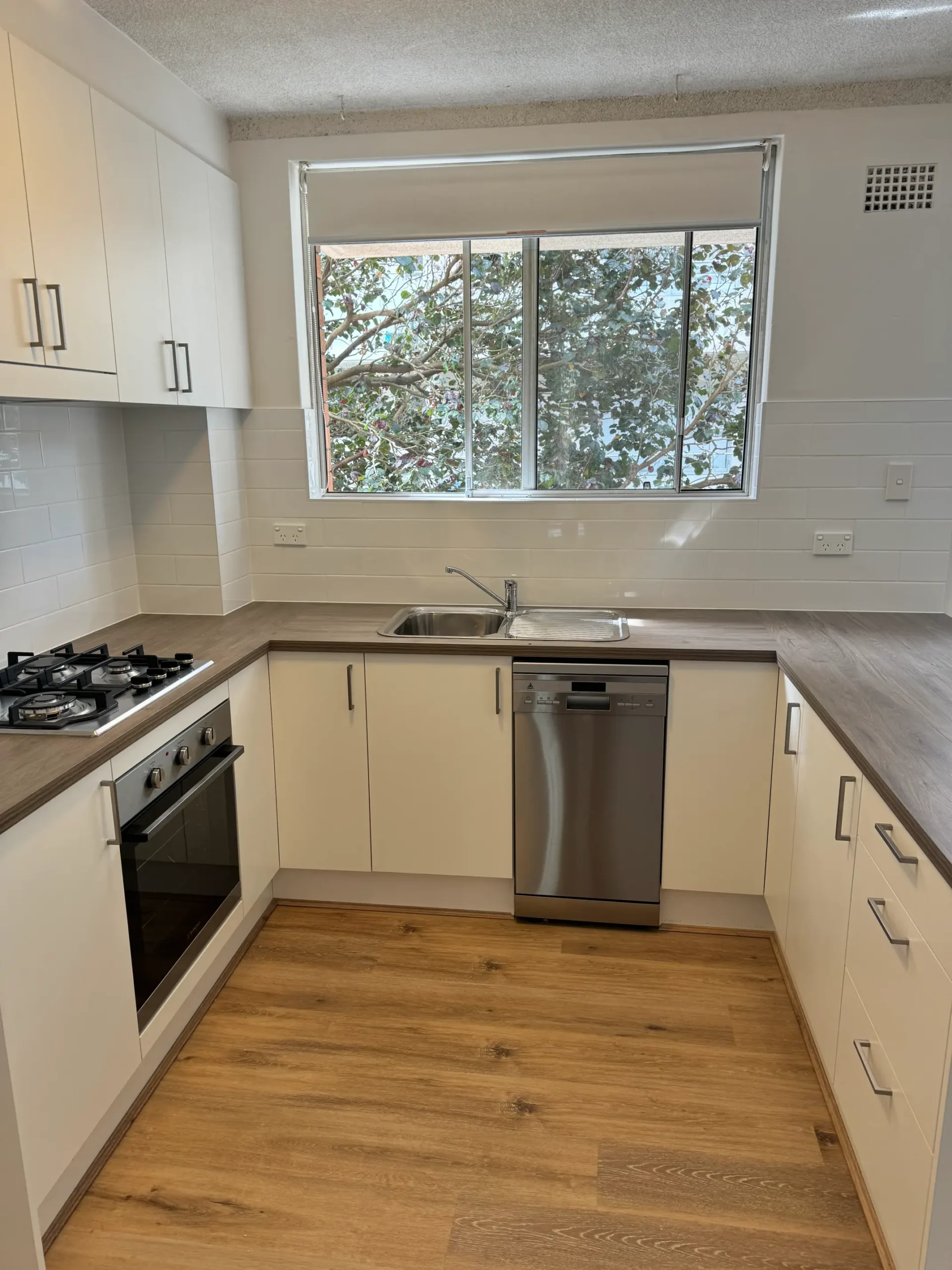 Freshwater kitchen with white refaced doors, subway tile splashback, sink and stainless dishwasher