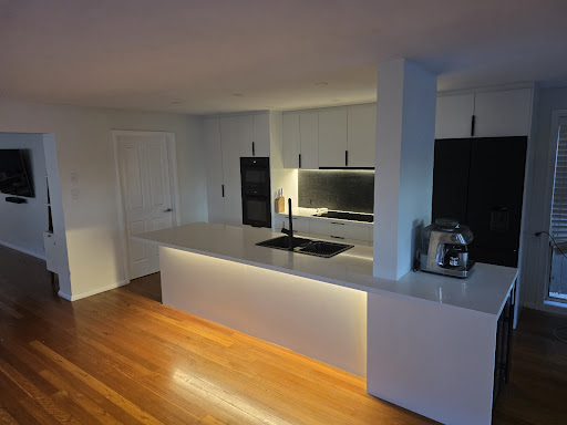 Modern kitchen renovation in Dee Why featuring a white island bench, under-counter lighting, and custom cabinetry.